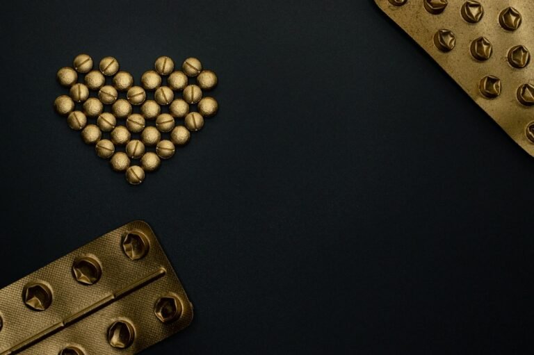 Creative arrangement of gold pills forming a heart shape against a black background, with space for text.