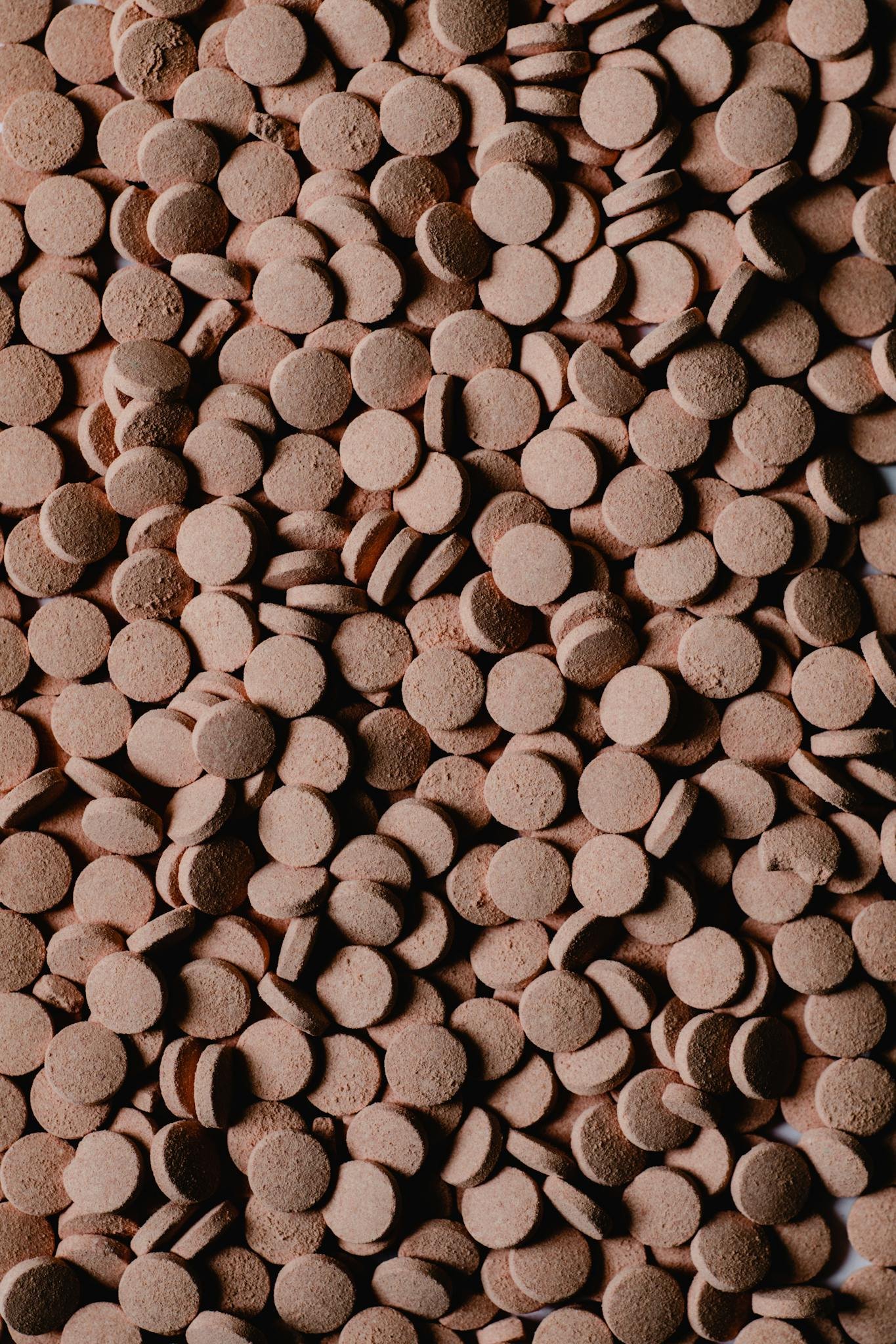 Detailed close-up of numerous brown round pills creating a textured surface.